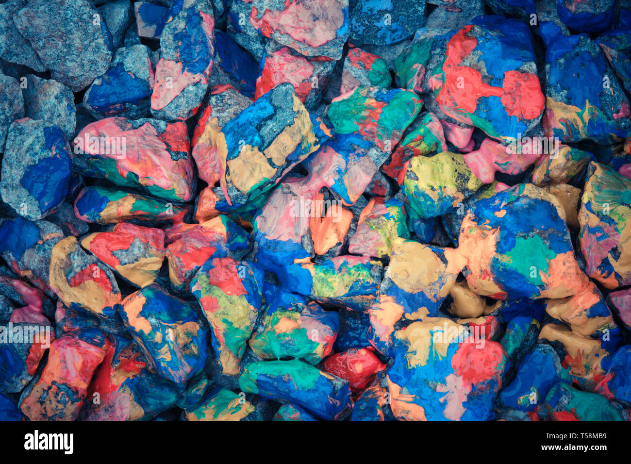 Pebbles painted colored paints in bright spots Stock Photo
