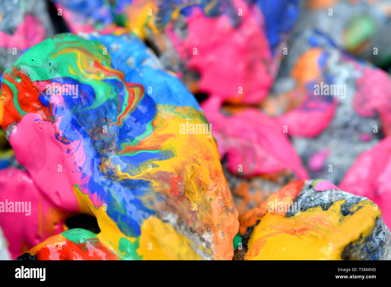 rocks covered with colorful paint close-up. Stones in the paint with streaks. Abstract background Stock Photo