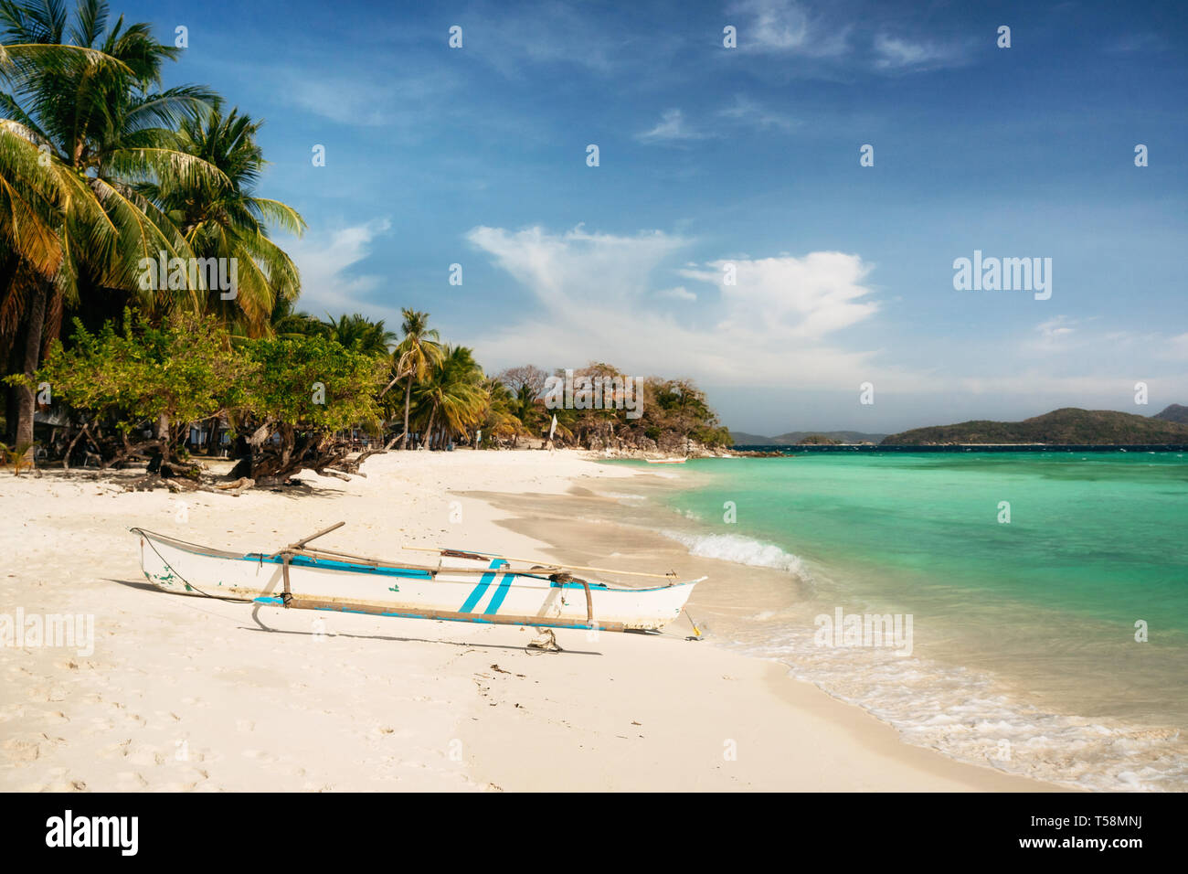 Tropical Malcapuya island with traditional philippines bangka boat, azure water and white sand beach. Travel vacation at Philippines. Stock Photo
