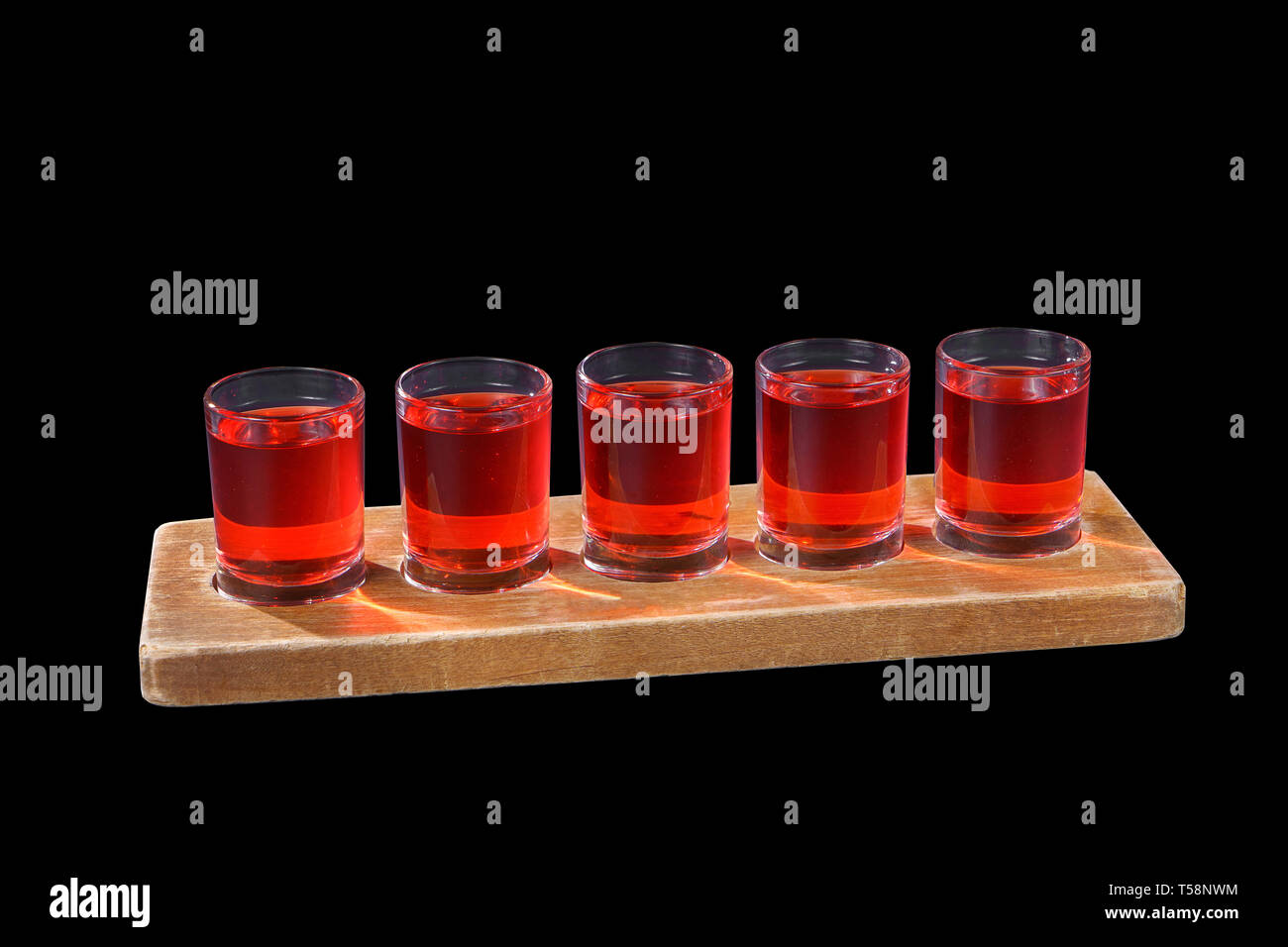 Red, same color transparent cocktails, a set of shots in one row, five servings on a wooden stand, substrate, Side view, Isolated black background, Dr Stock Photo