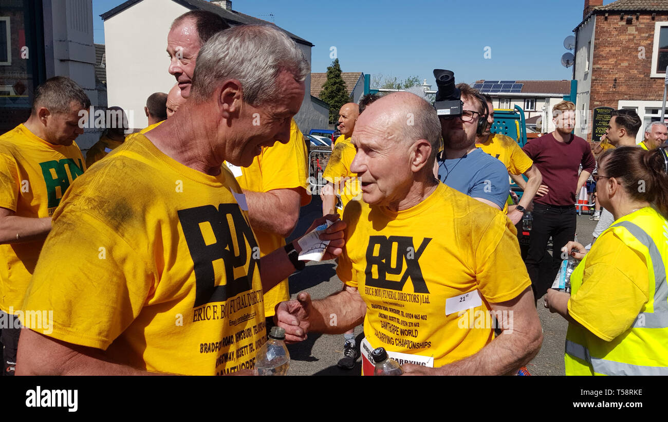 David Page, 72 (right), the oldest-ever competitor in the World Coal Carrying Championships, speaking to a fellow competitor after he was cheered as he carried his 50kg (7st 12lb) load in sweltering conditions for the traditional bank holiday event in Gawthorpe, West Yorkshire. Stock Photo