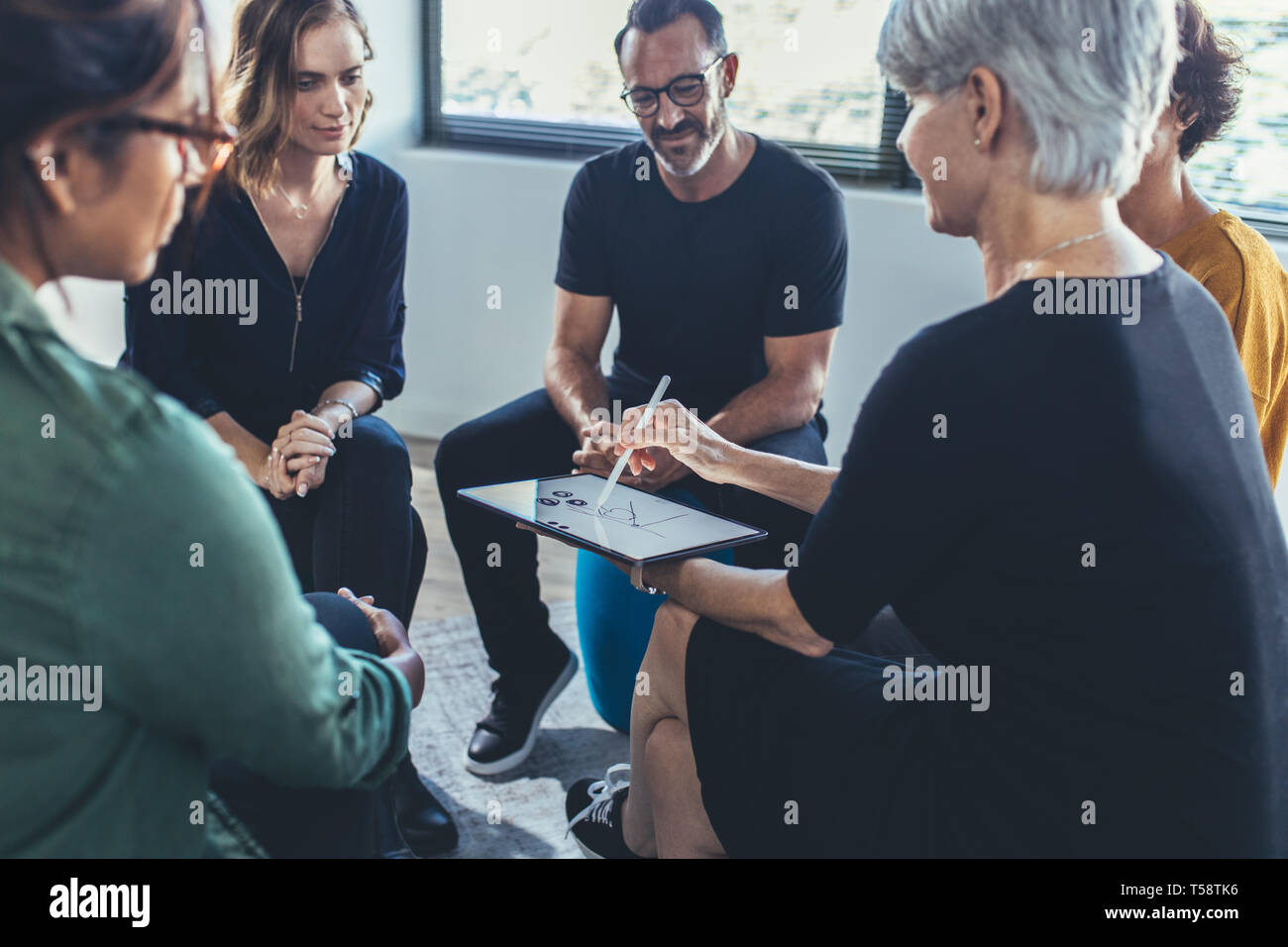 Multi-ethnic group of people sitting together having a group discussion. Business people having a meeting on new working strategies. Stock Photo