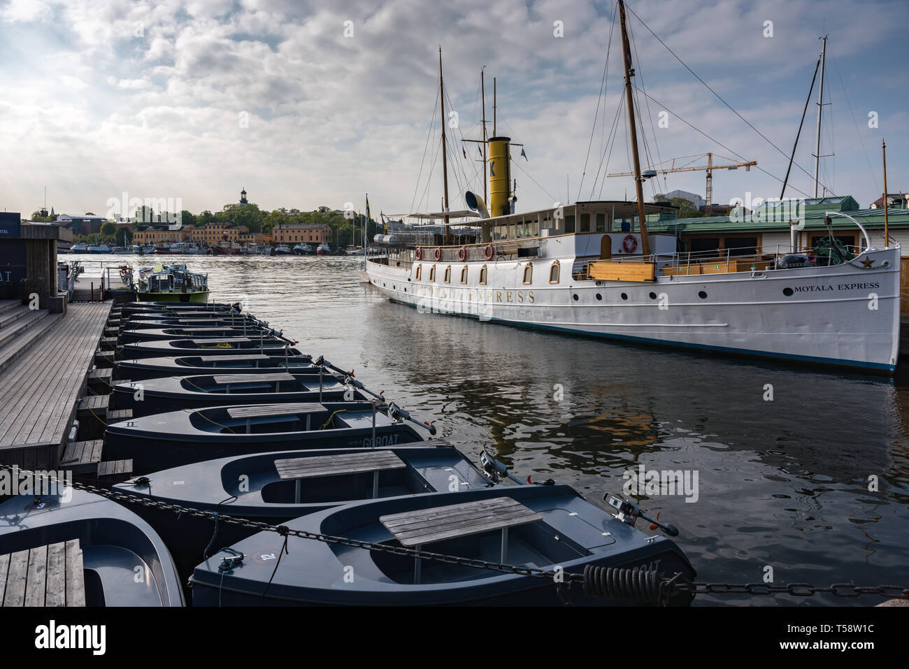 A line of Goboat picnic boats moored in Ladugårds-landsviken by the historic SS Motala Express. The recycled plastic boats are powered by solar batter Stock Photo