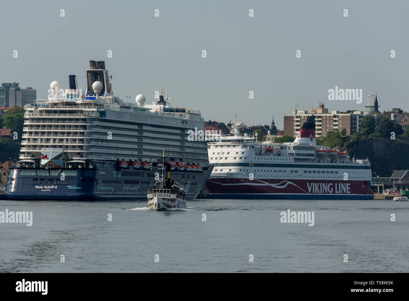 Cruise ships Gabriella and Mein Schiff 4 dwarf the historic steamship SS Storskär in the Baltic off Södermalm in Stockholm Stock Photo