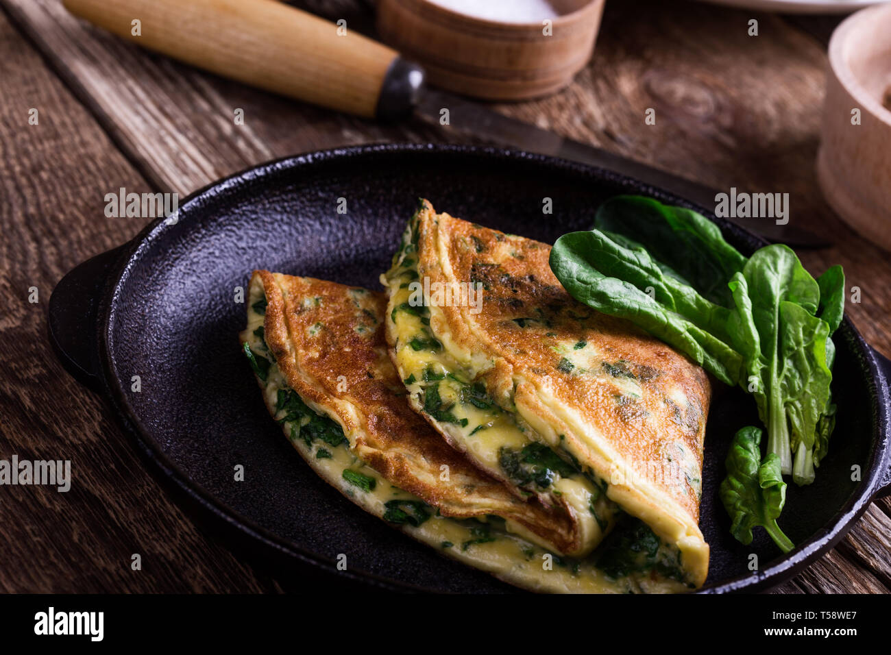 Spinach omelette in cast iron skillet, healthy vegetarian breakfast or brunch on wooden rustic table, close up, selective focus Stock Photo