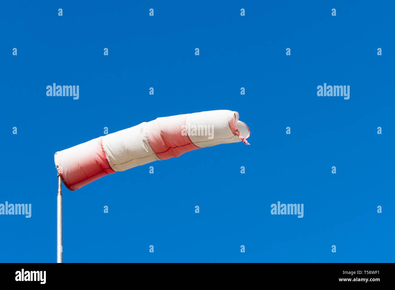 Red White windsock indicating from where the wind comes with a blue background Stock Photo