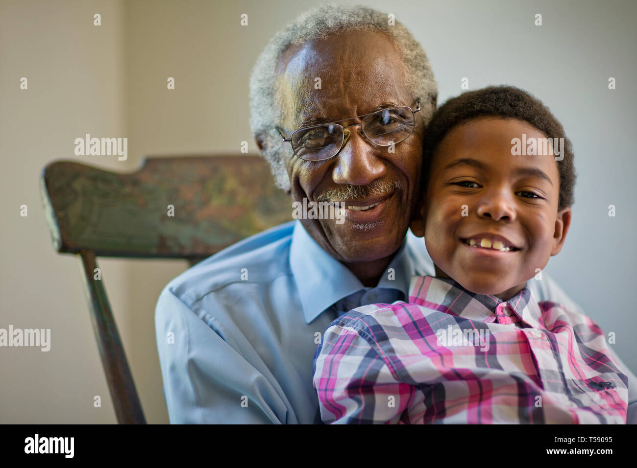 Senior man sitting in a rocking chair with his grandson. Stock Photo