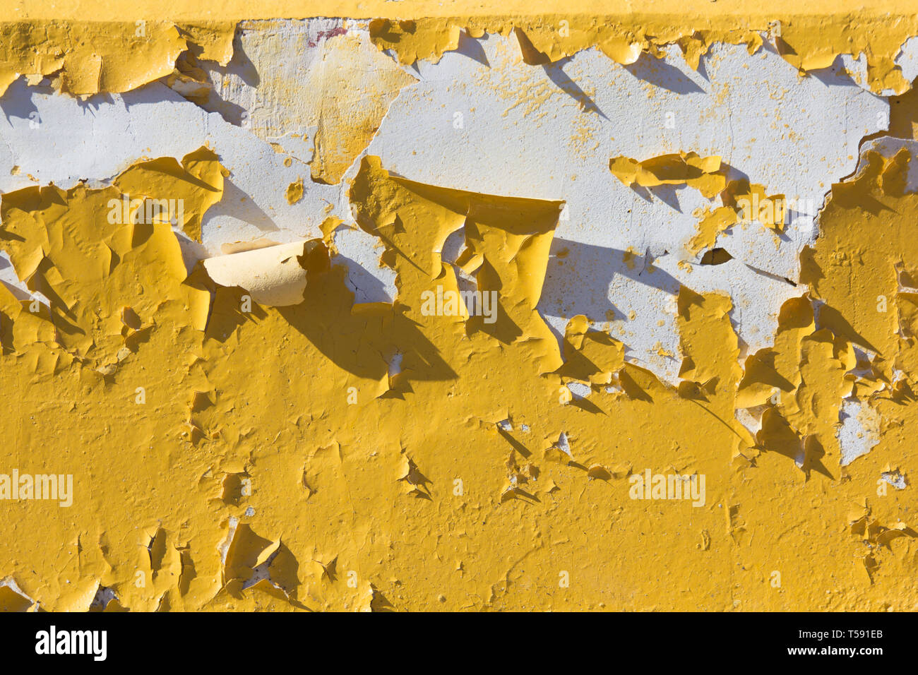 Yellow peeling paint from the wall. Texture paint cracks. Yellow paint. Old wall Stock Photo