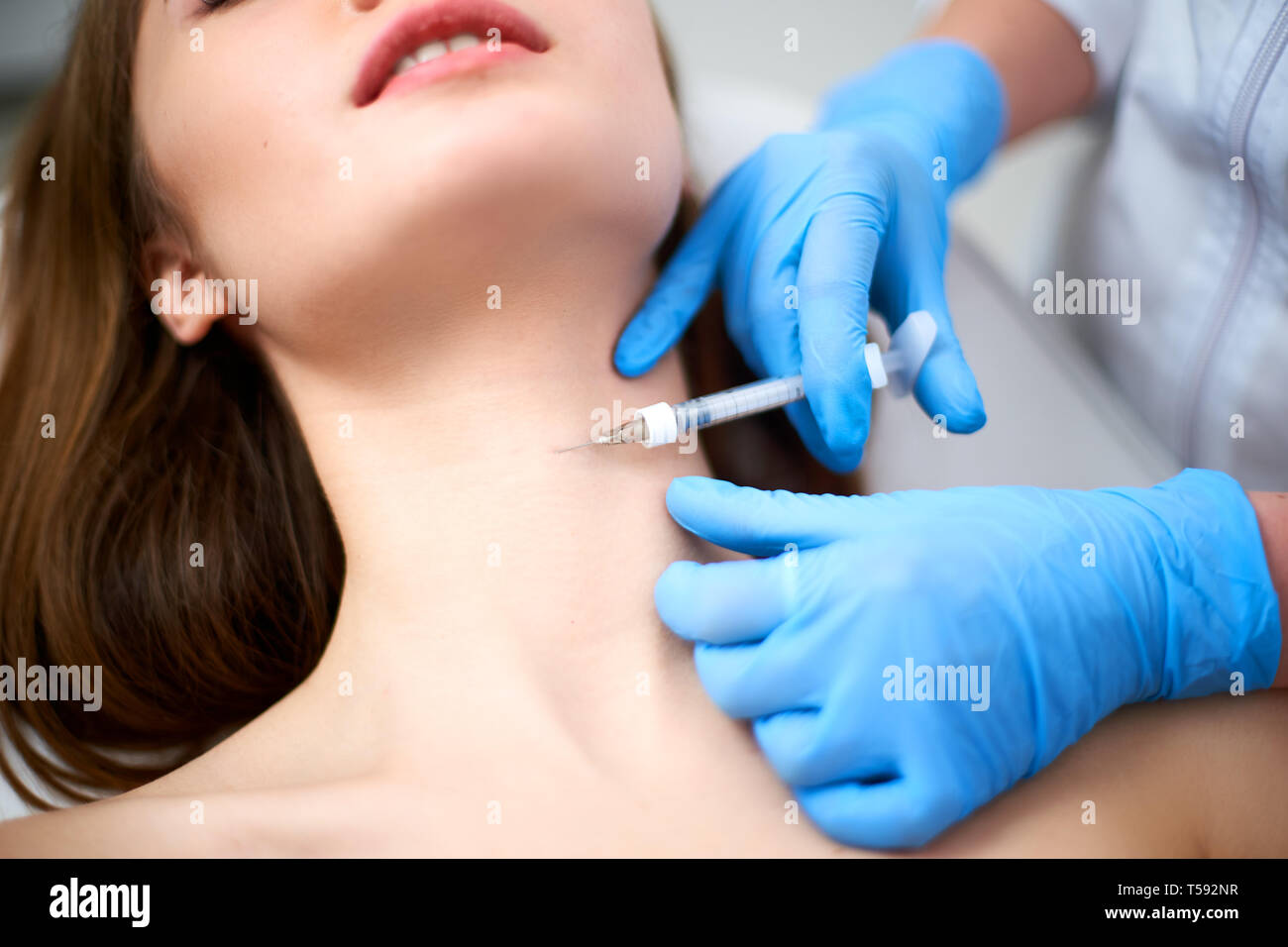 Beautician doctor with botulinum toxin syringe making injection to platysmal bands. Neck rejuvenation mesotherapy. Anti-aging treatment and face lift Stock Photo