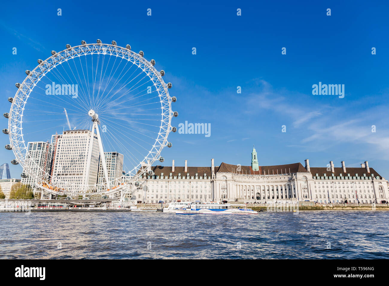 England London - April 20, 2019: London Eye near County Hall in summer view from Thame river boat cruise Stock Photo