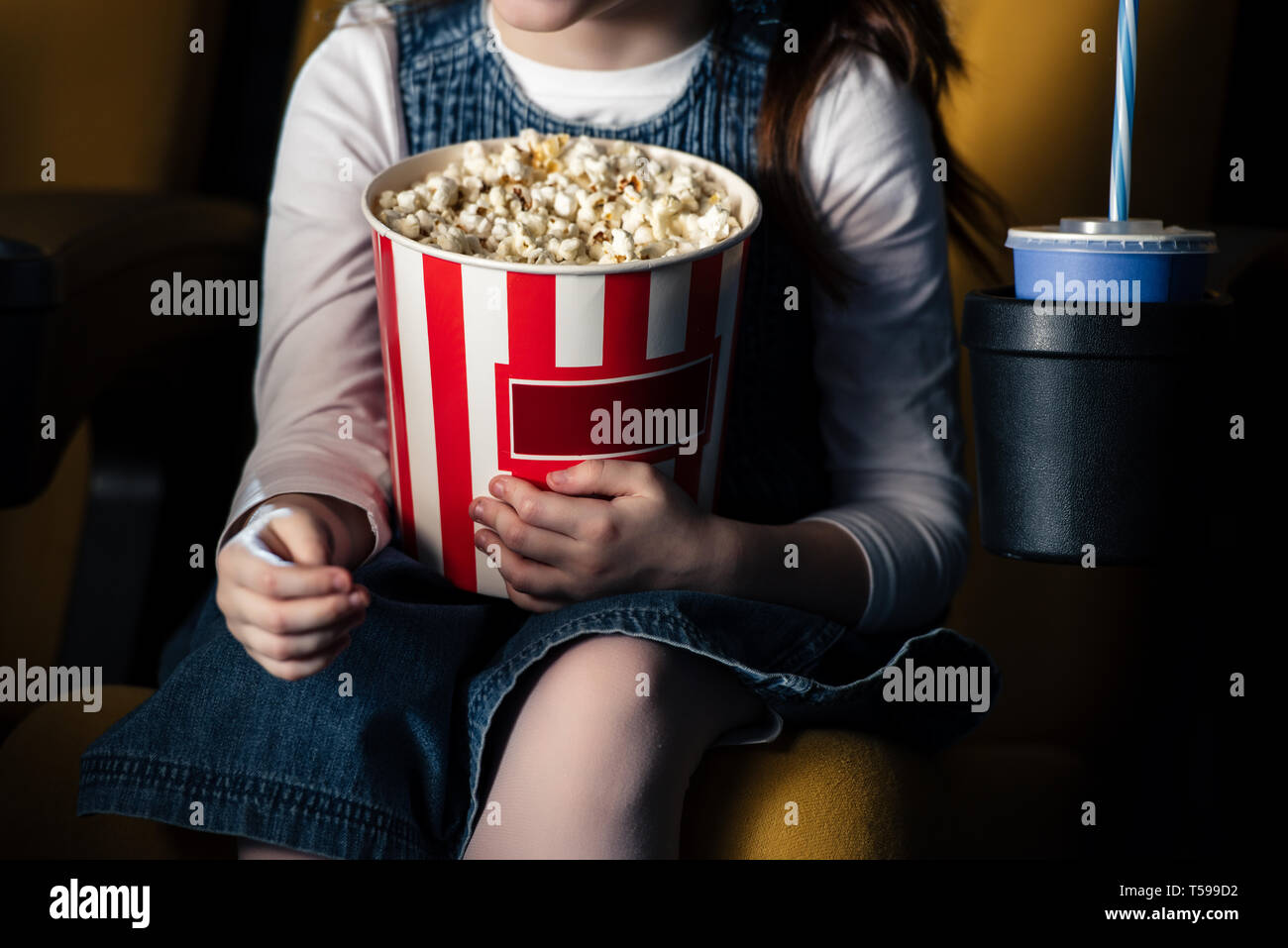 partial view of child holding paper cup with popcorn in cinema Stock Photo