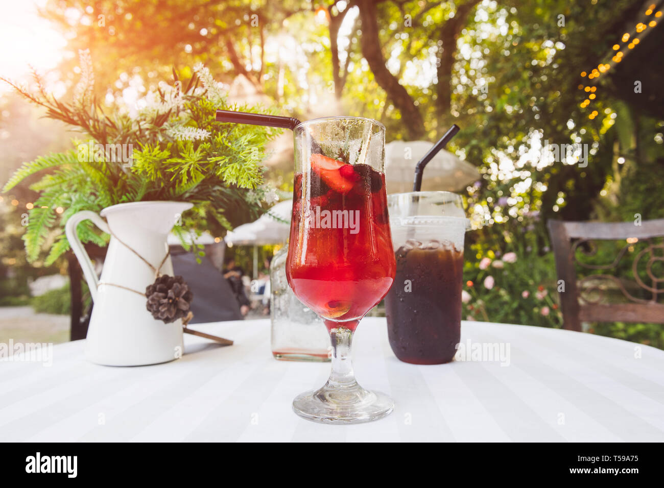 Ice cold berry fruit tea drink and ice coffee with outdoor sunset lighting. Stock Photo