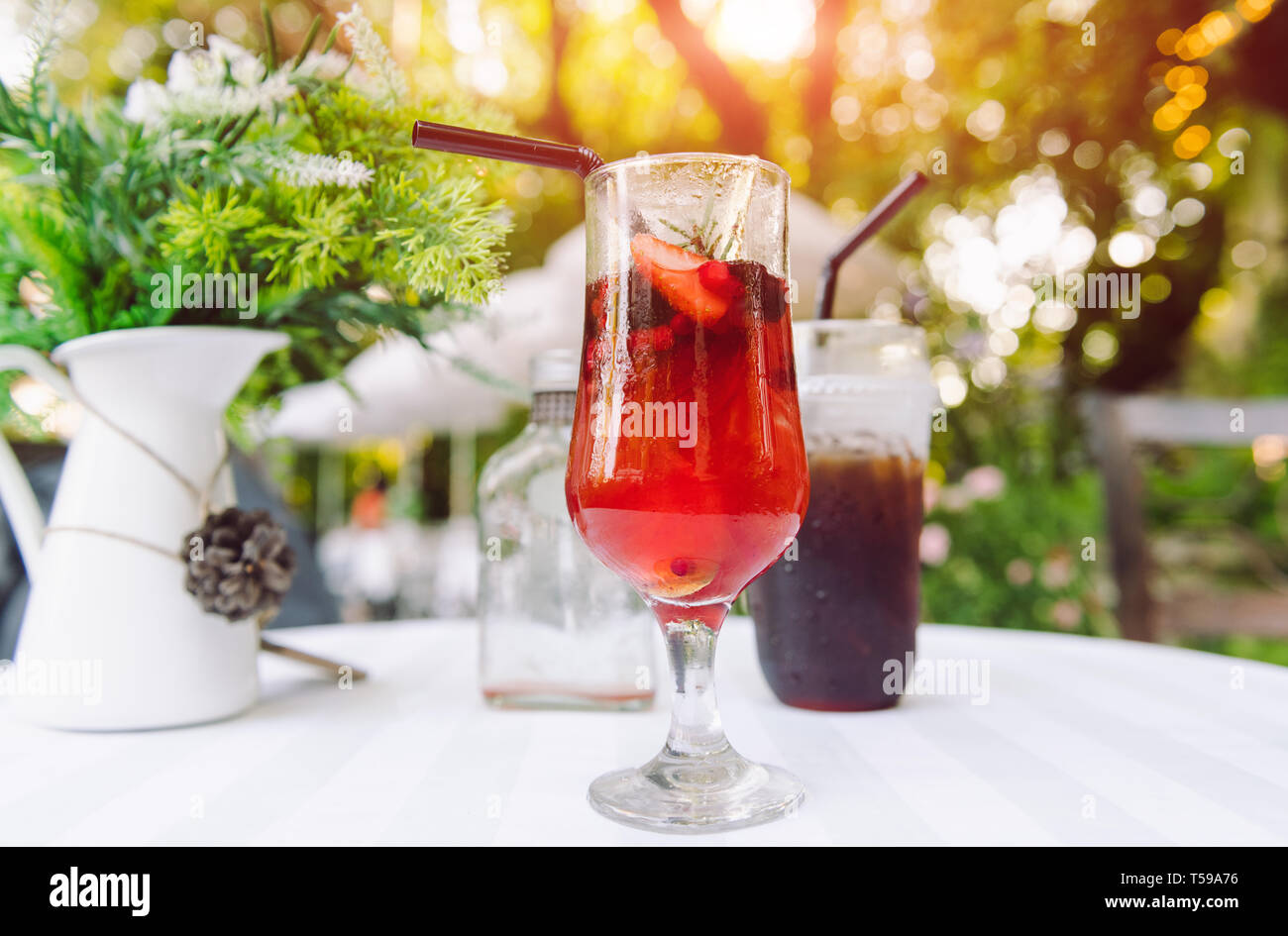 Ice cold berry fruit tea drink and ice coffee with outdoor sunset lighting. Stock Photo