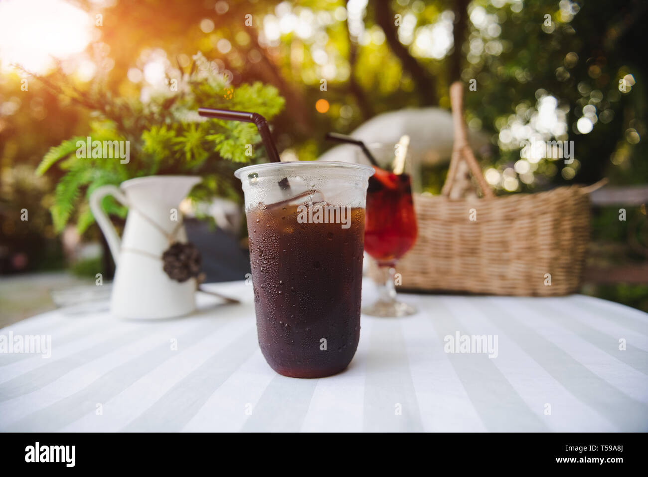 Ice cold berry fruit tea drink and ice coffee with outdoor sunset lighting. Stock Photo