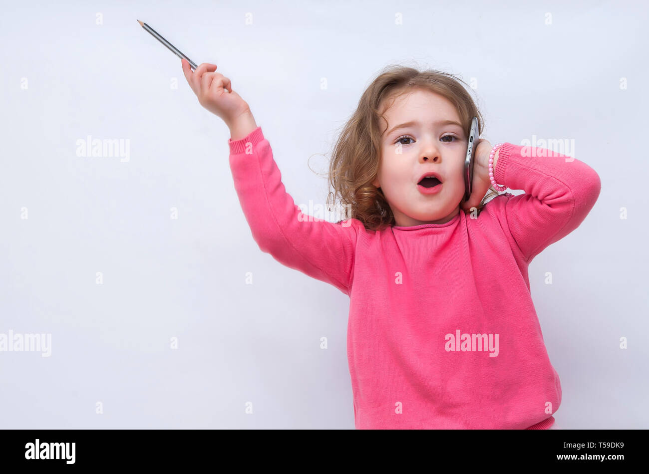 Happy little girl speaking by cell phone and raised a hand up Stock Photo