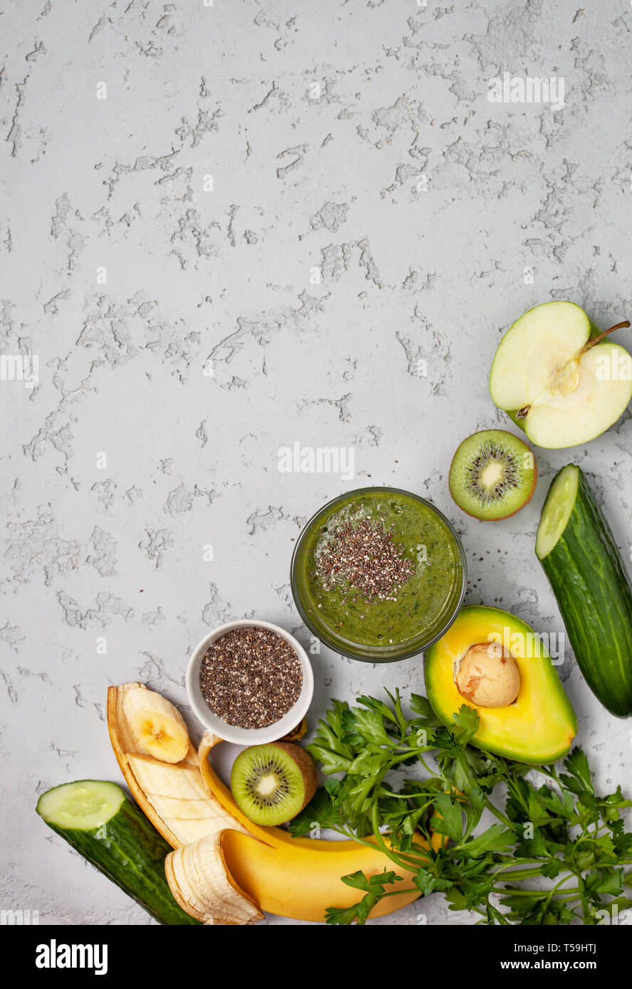 green smoothie in a glass, fresh fruits and vegetables on a gray background. view from above. copy space Stock Photo