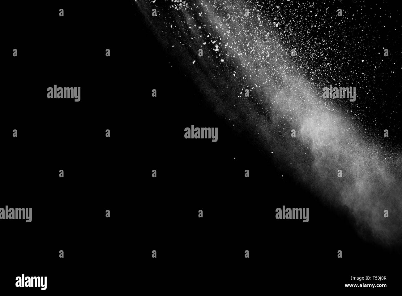 White dust particles exhale in the air. Motion powder burst in dark background. Stock Photo