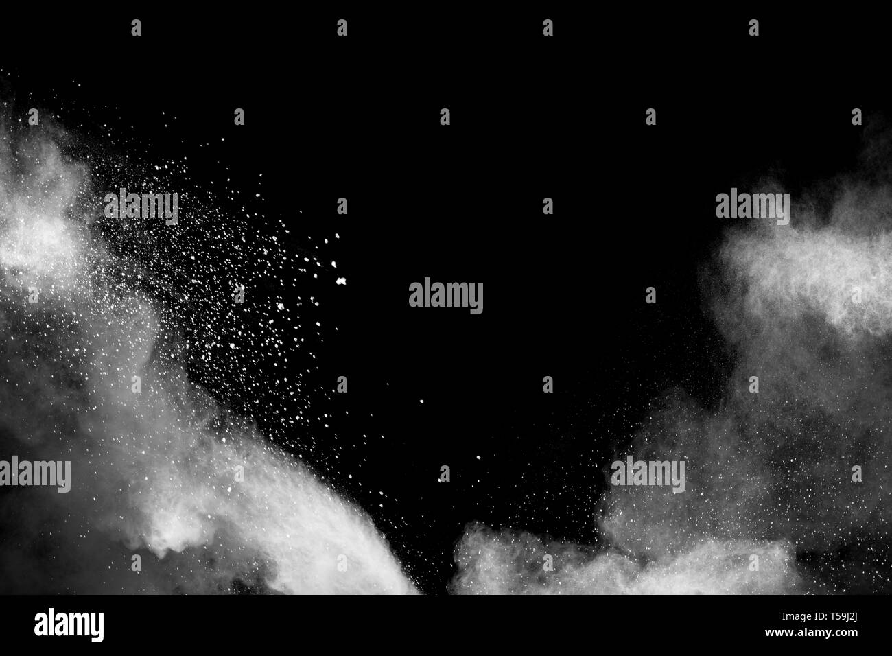 White dust particles exhale in the air. Motion powder burst in dark