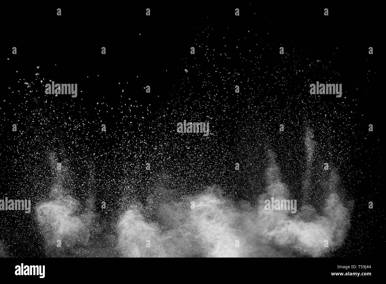 White dust particles exhale in the air. Motion powder burst in dark