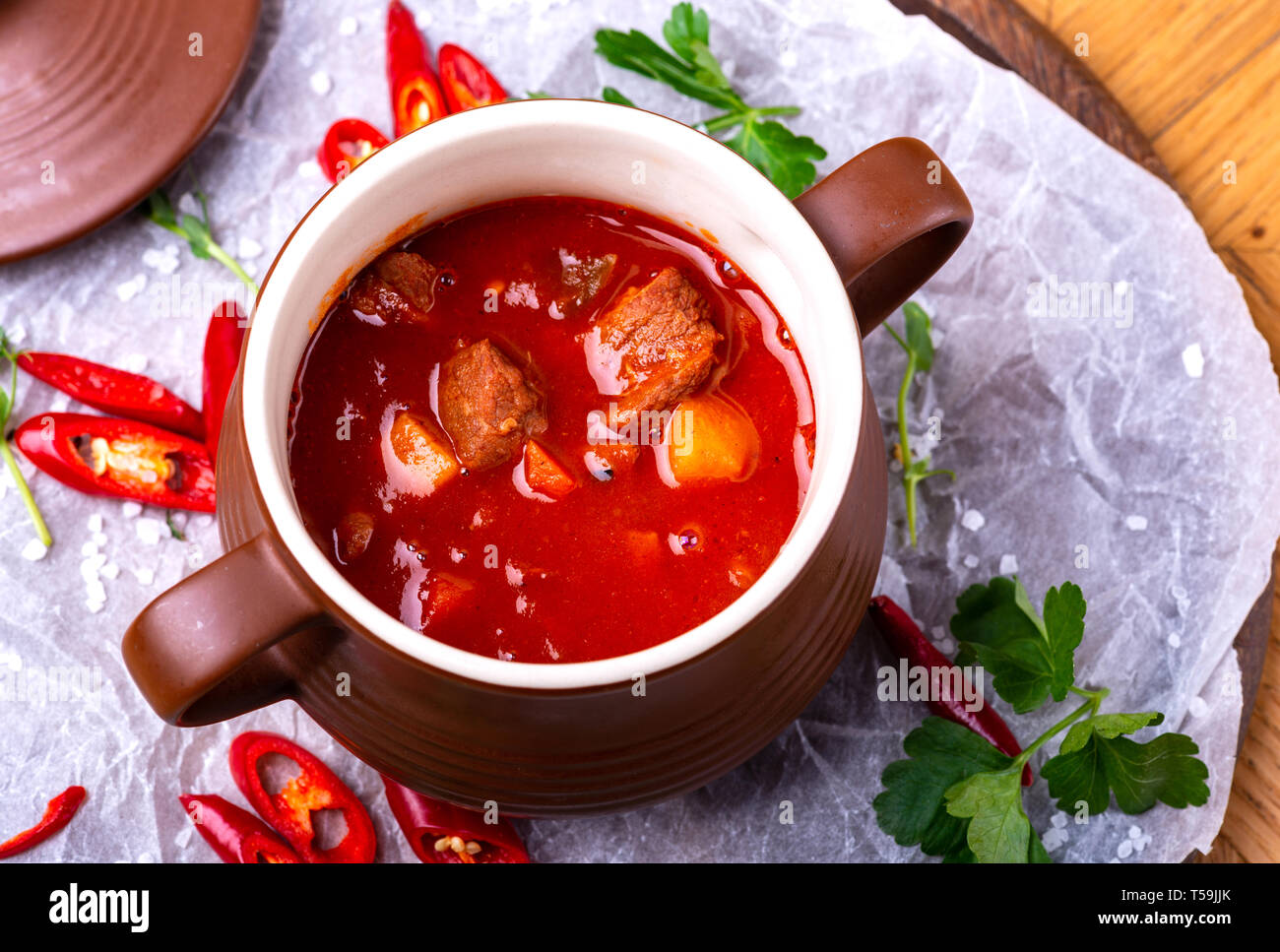 Tasty Hungarian Hot Goulash Soup Bograch or Gulas Lamb Meat Stew on Wooden Surface at Restaurant. Traditional Food. Stock Photo