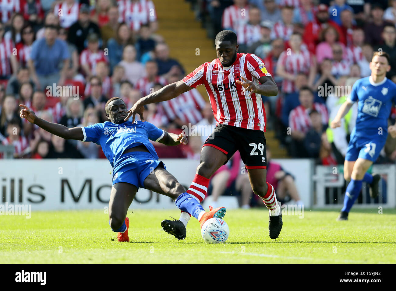 Tranmere Rovers Zoumana Bakayogo tackles Lincoln City's John Akinde during the Sky Bet League Two match at Sincil Bank, Lincoln. Stock Photo