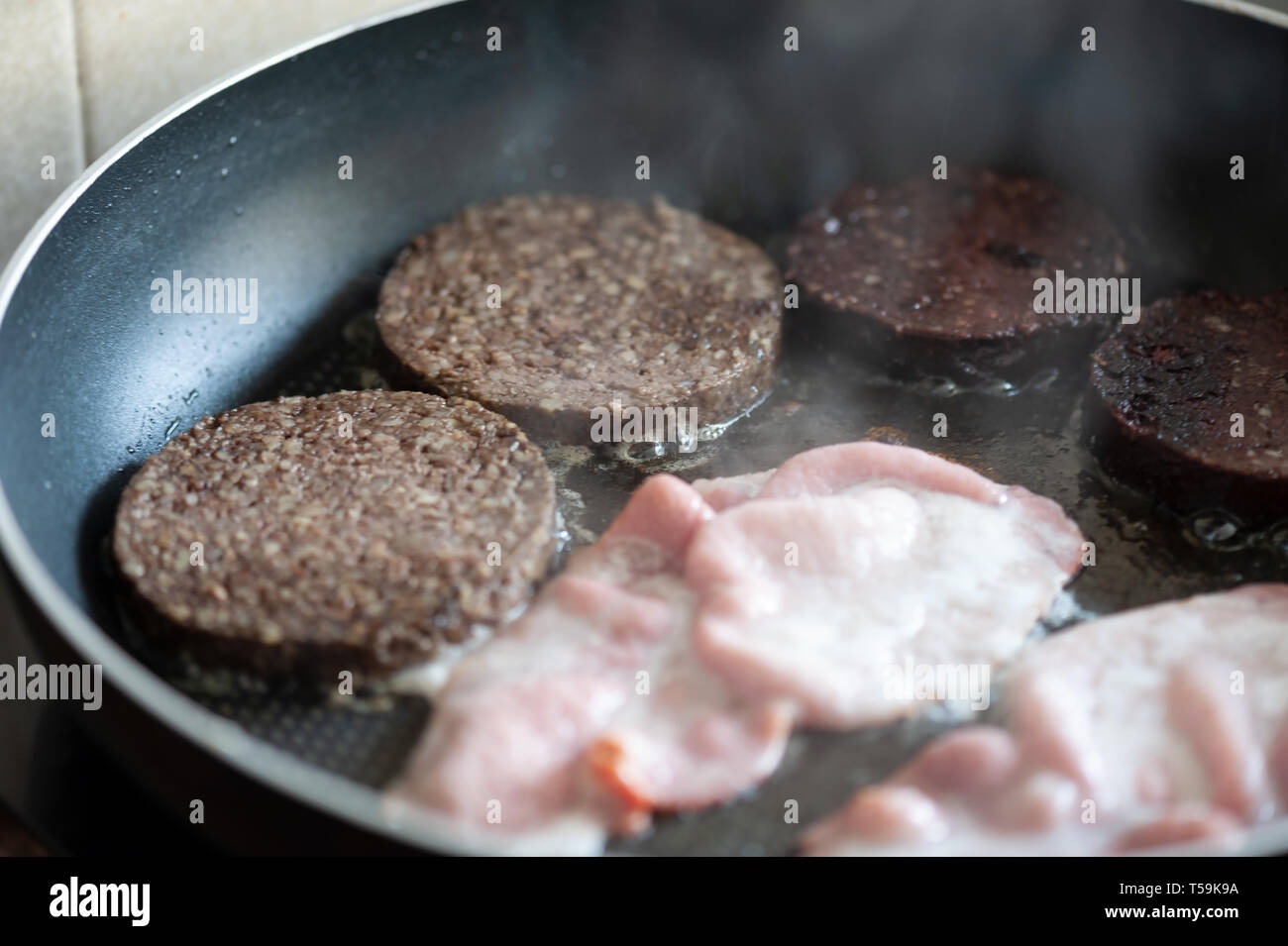 https://c8.alamy.com/comp/T59K9A/bacon-sizzling-in-a-pan-with-black-pudding-and-sliced-haggis-a-fried-breakfast-in-the-making-T59K9A.jpg