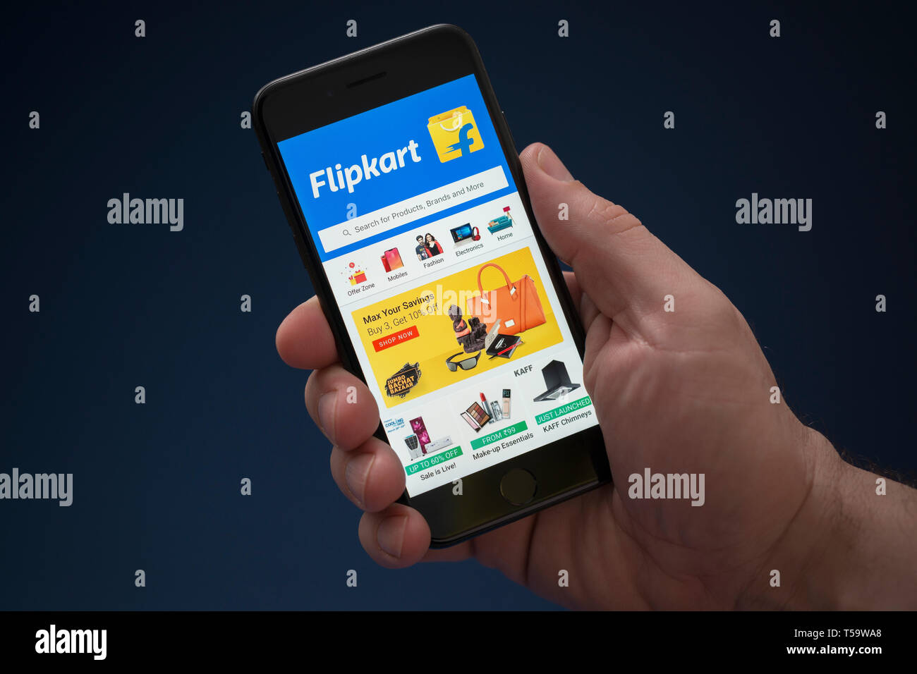 A man looks at his iPhone which displays the Flipkart logo (Editorial use only). Stock Photo