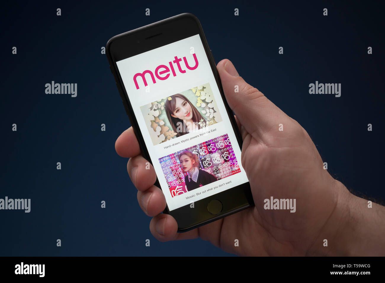 A man looks at his iPhone which displays the Meitu logo (Editorial use only). Stock Photo