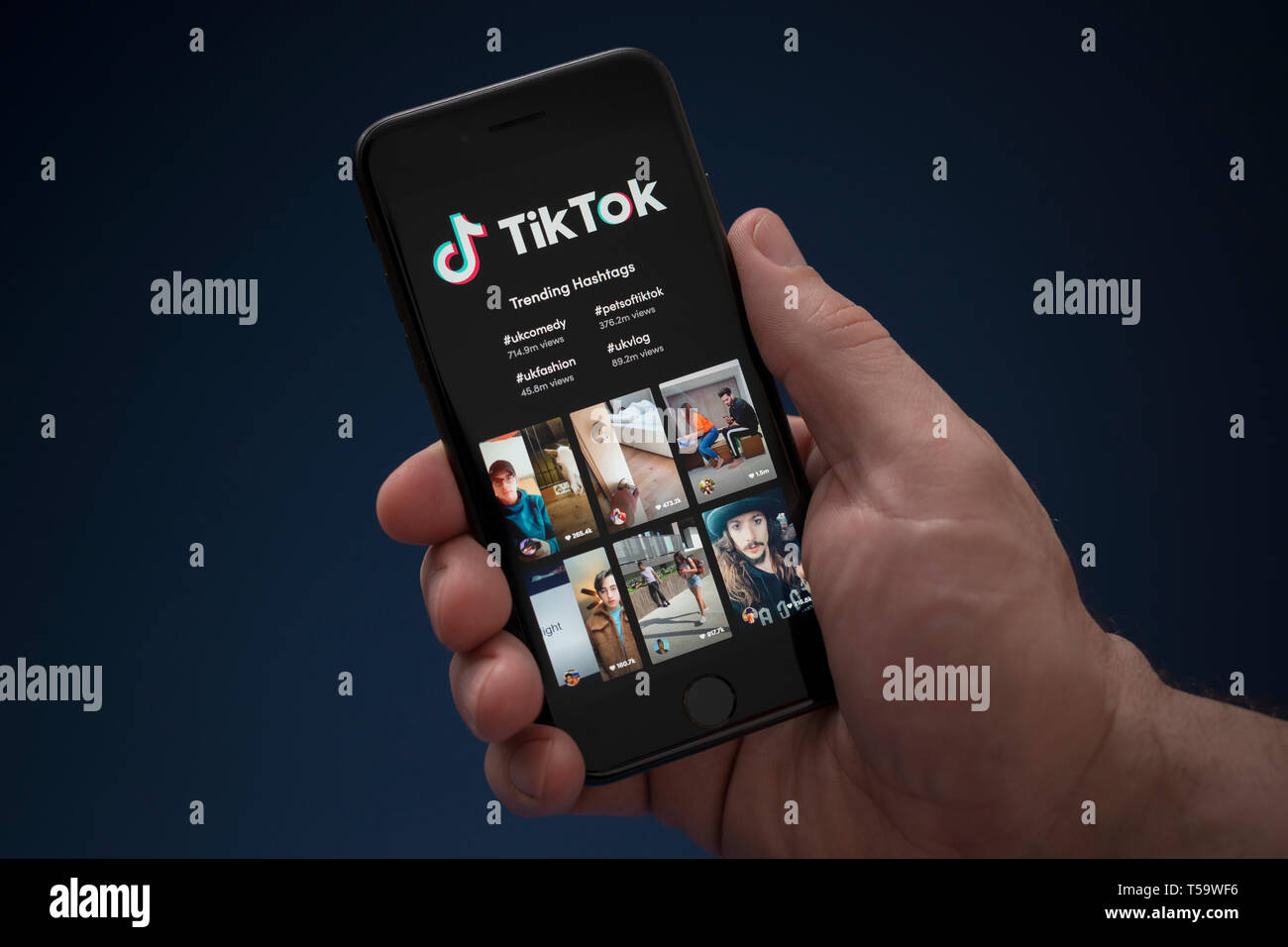 A man looks at his iPhone which displays the Tik Tok logo (Editorial