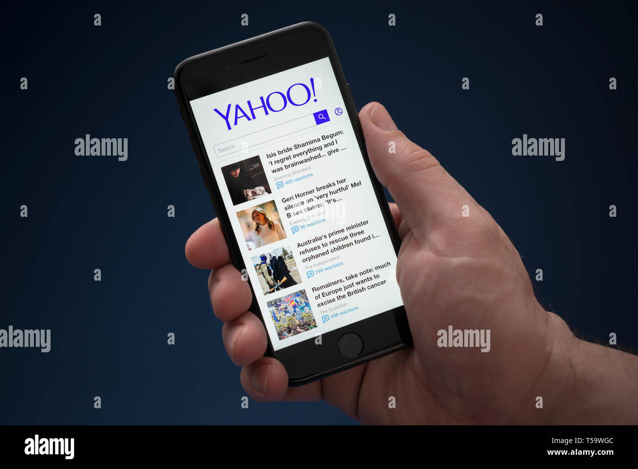 A man looks at his iPhone which displays the Yahoo logo (Editorial use only). Stock Photo