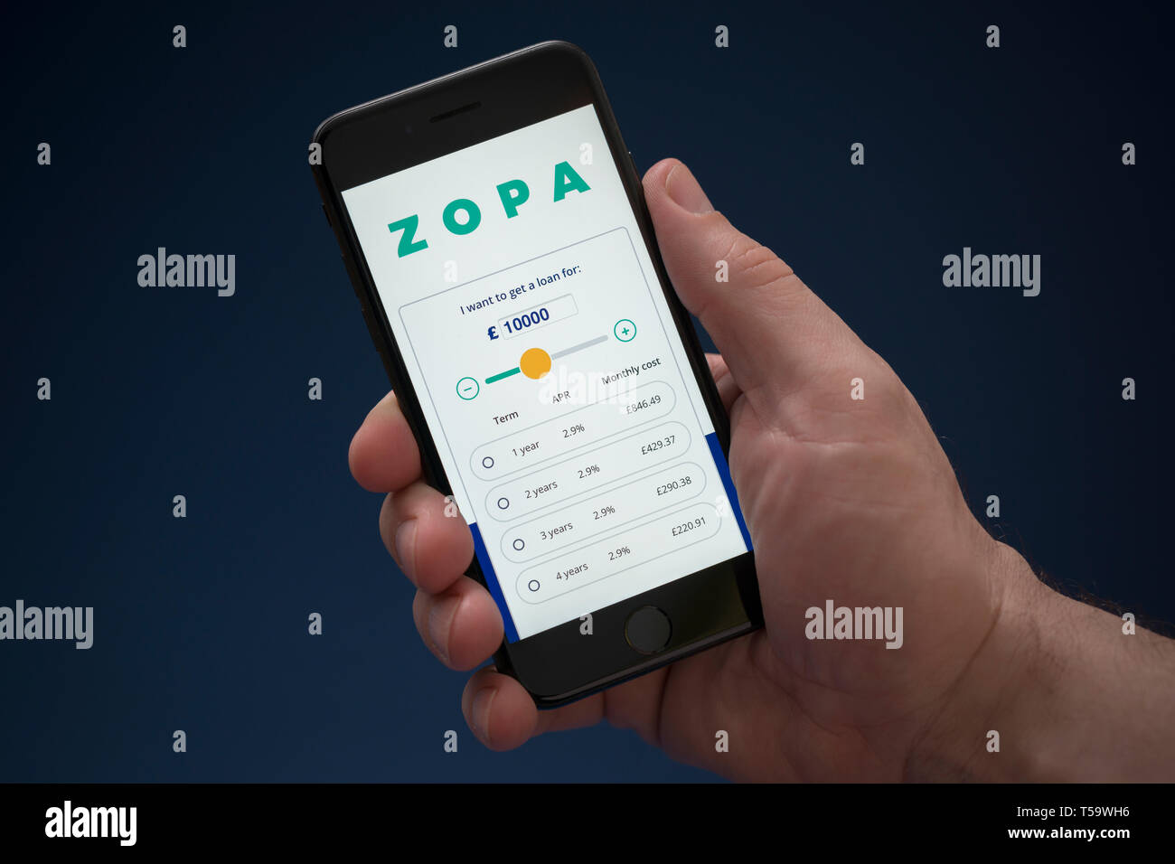 A man looks at his iPhone which displays the Zopa logo (Editorial use only). Stock Photo