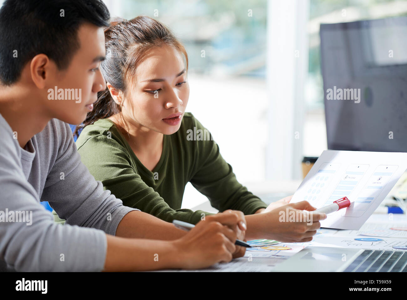 Designer pointing at sketches of interface Stock Photo