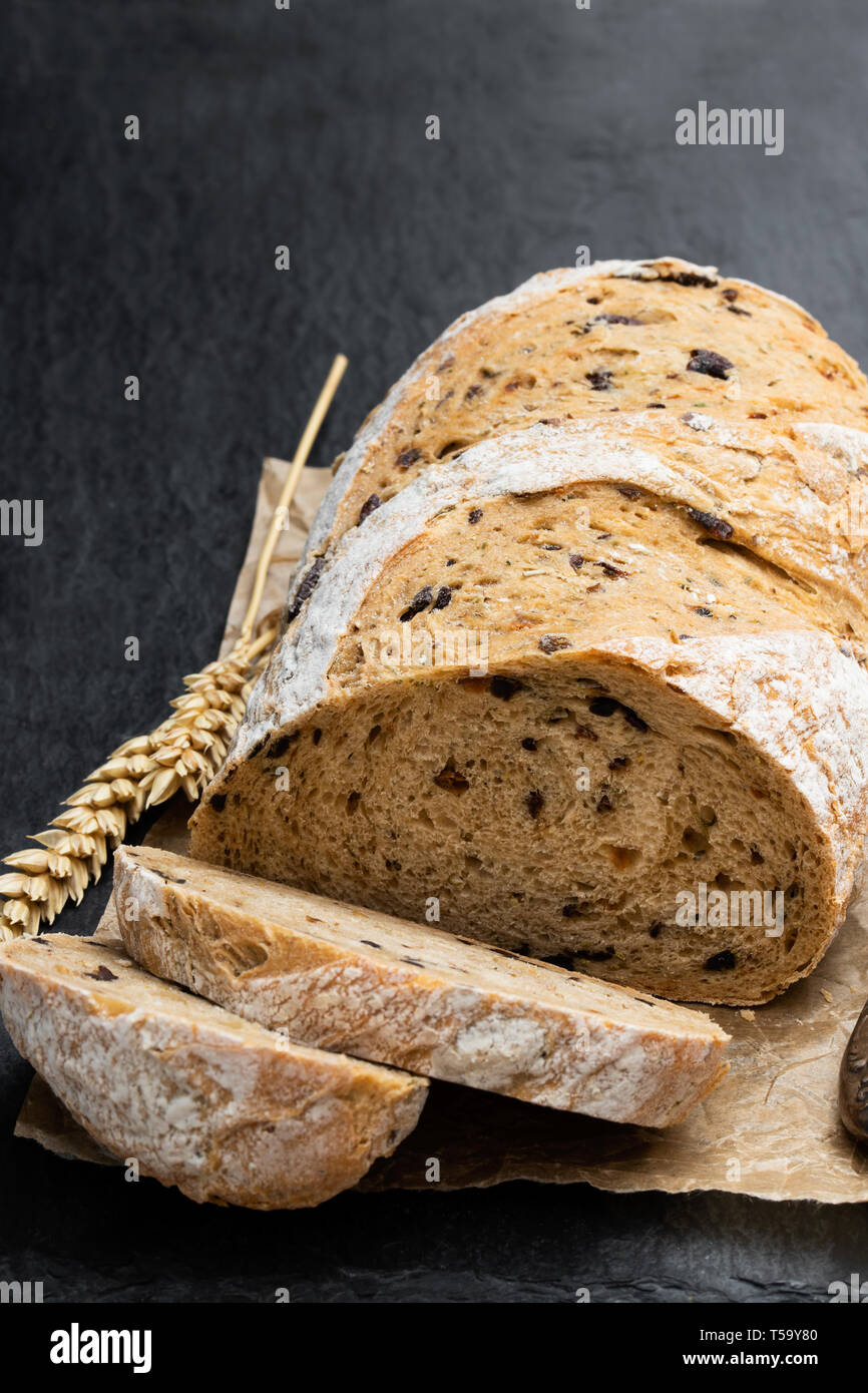 Homemade rye loaf bread with olives on black stone background Stock
