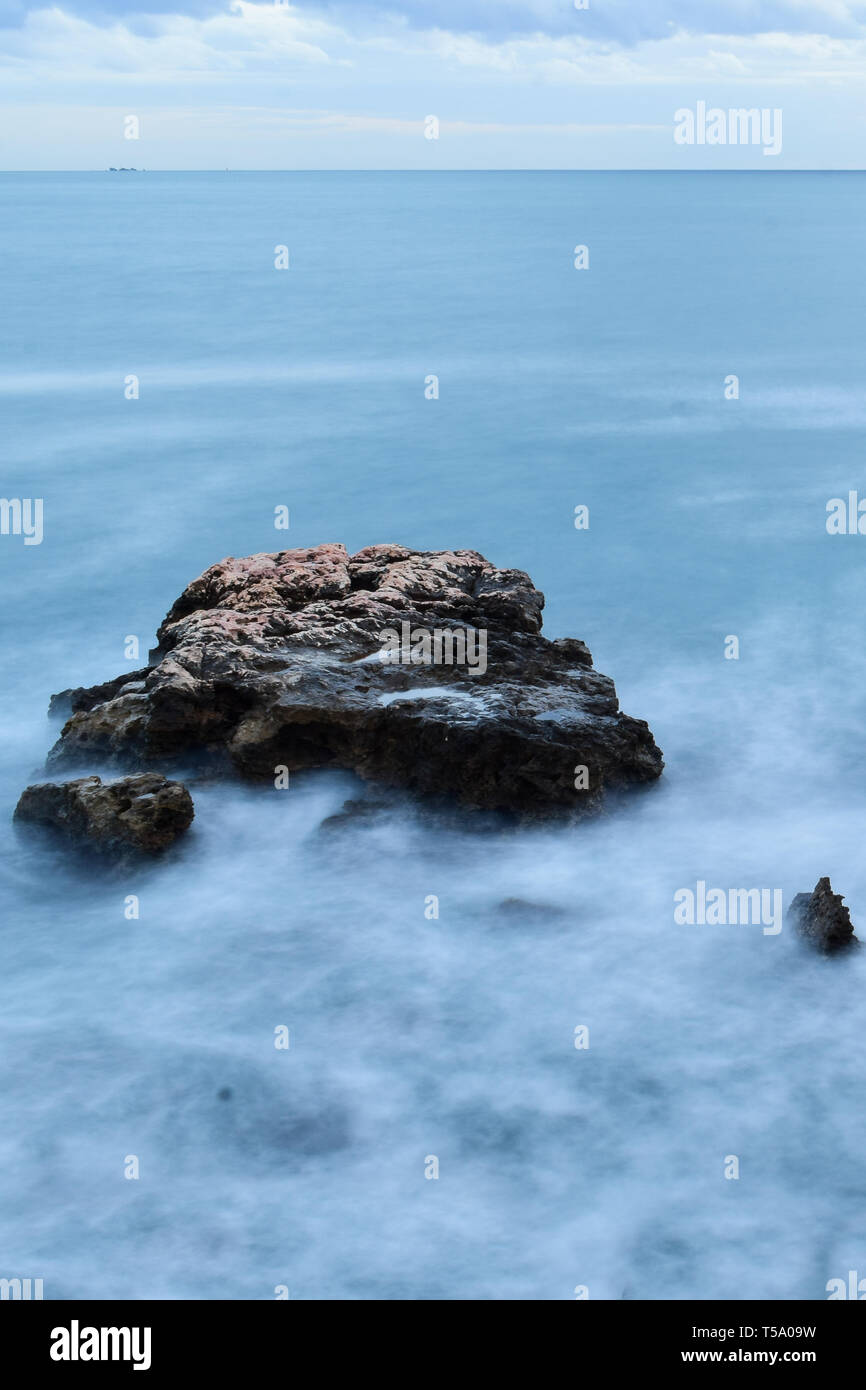 Atmospheric misty water swirling around rock in the Mediterranean Sea Stock Photo