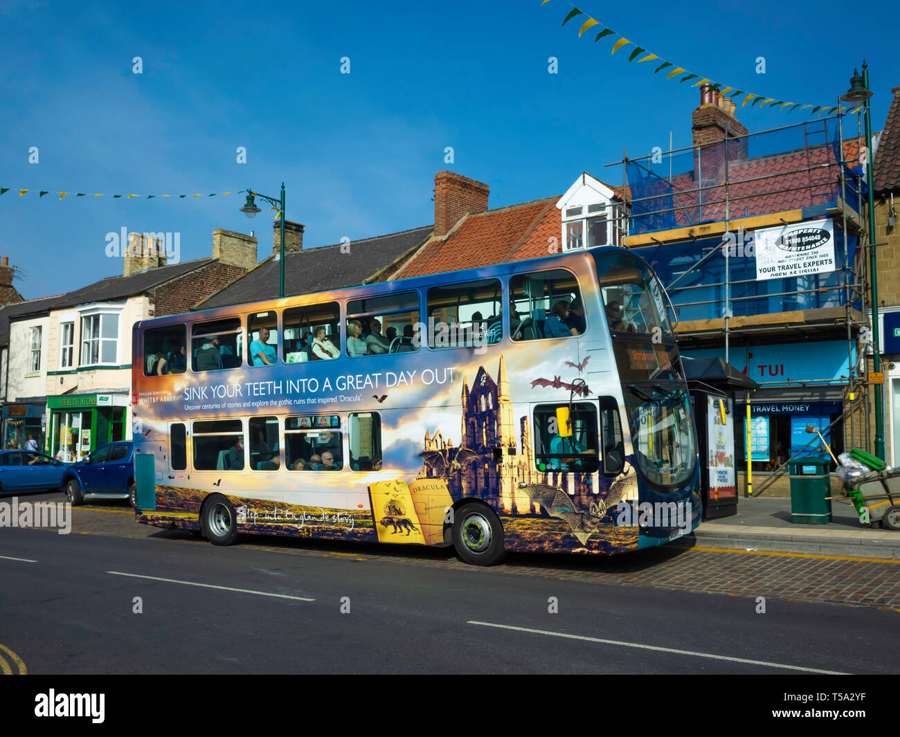A double decker Midddlsbrough to Whitby bus at Guisborough North Yorkshire the bus covered in promotional images of Tourist Attractions in Whitby Stock Photo