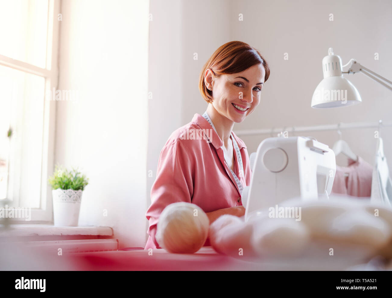 Young creative woman in a studio, working. A startup of small tailoring ...