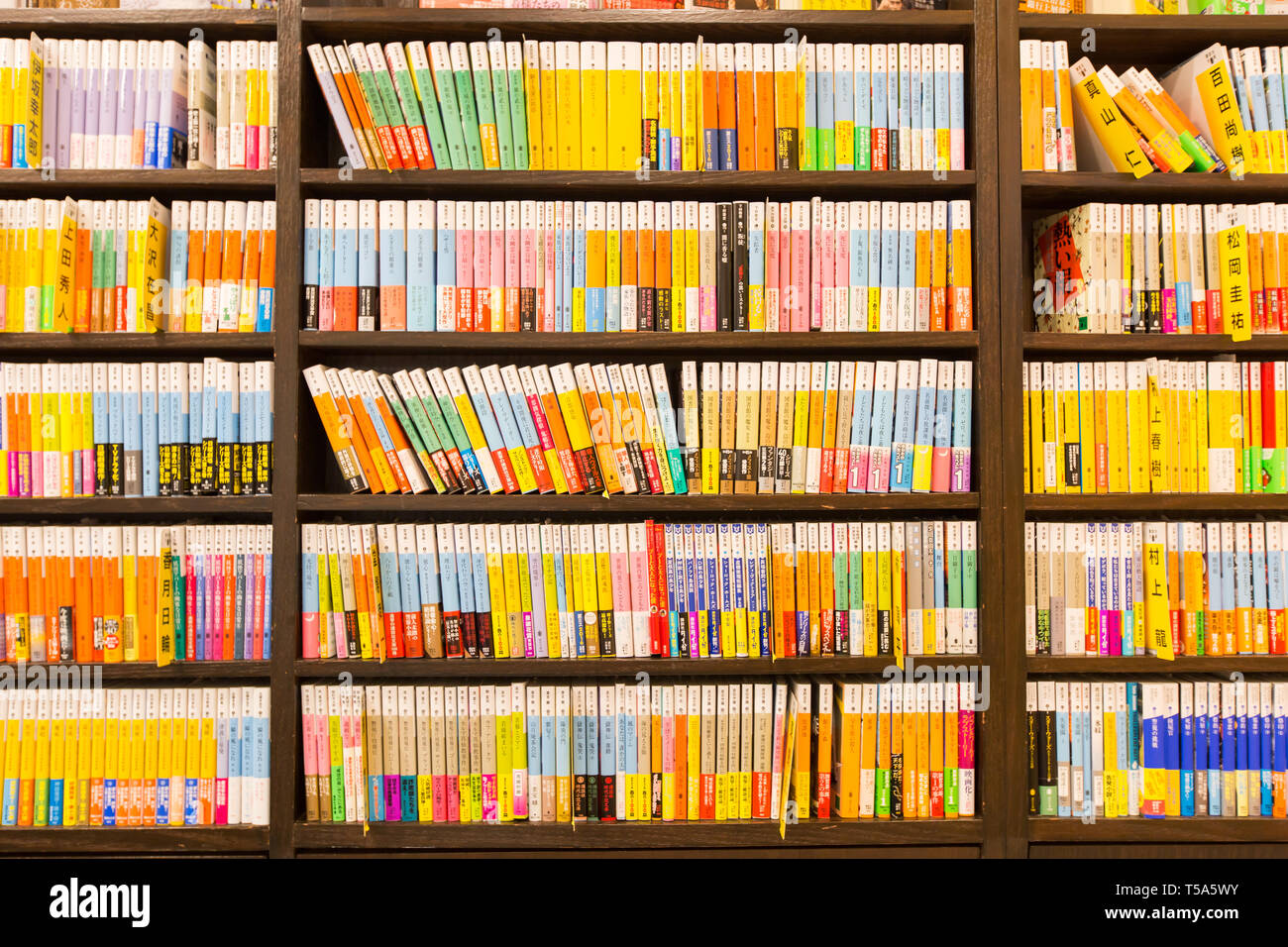 Rows of japanese books on shelves with warm ambience lighting. Stock Photo