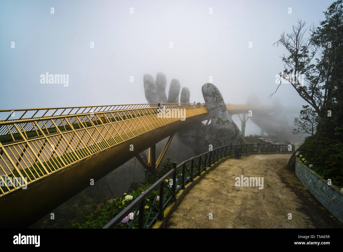 Ba Na Hill mountain resort, Danang city, Vietnam. The Golden Bridge is lifted by two giant hands in the tourist resort on Ba Na Hill in a foggy day at Stock Photo