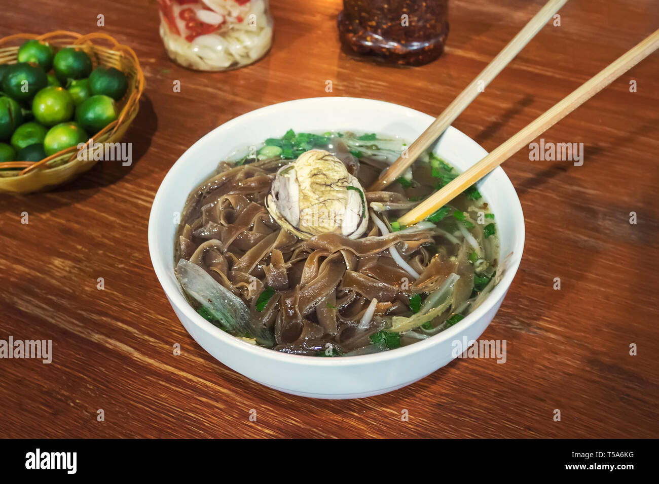 Fermented balut egg in a bowl. An exotic soup with Pho noodles on the table in the restaurant. Street food Vietnamese traditional cuisine. Stock Photo