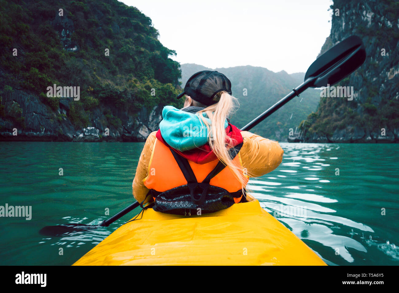 Girl kayaking on the seaside of Halong bay in Vietnam. Woman rowing
