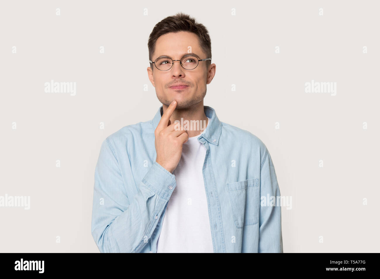 Thoughtful man in glasses isolated on grey background thinking Stock Photo