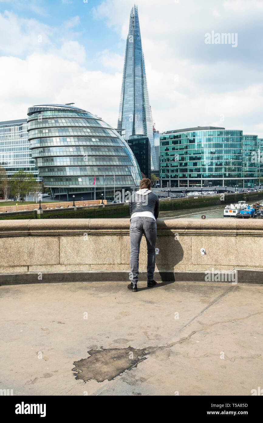 A person leaning on a parapet and gazing at iconic buildings on the South Bank in London. Stock Photo