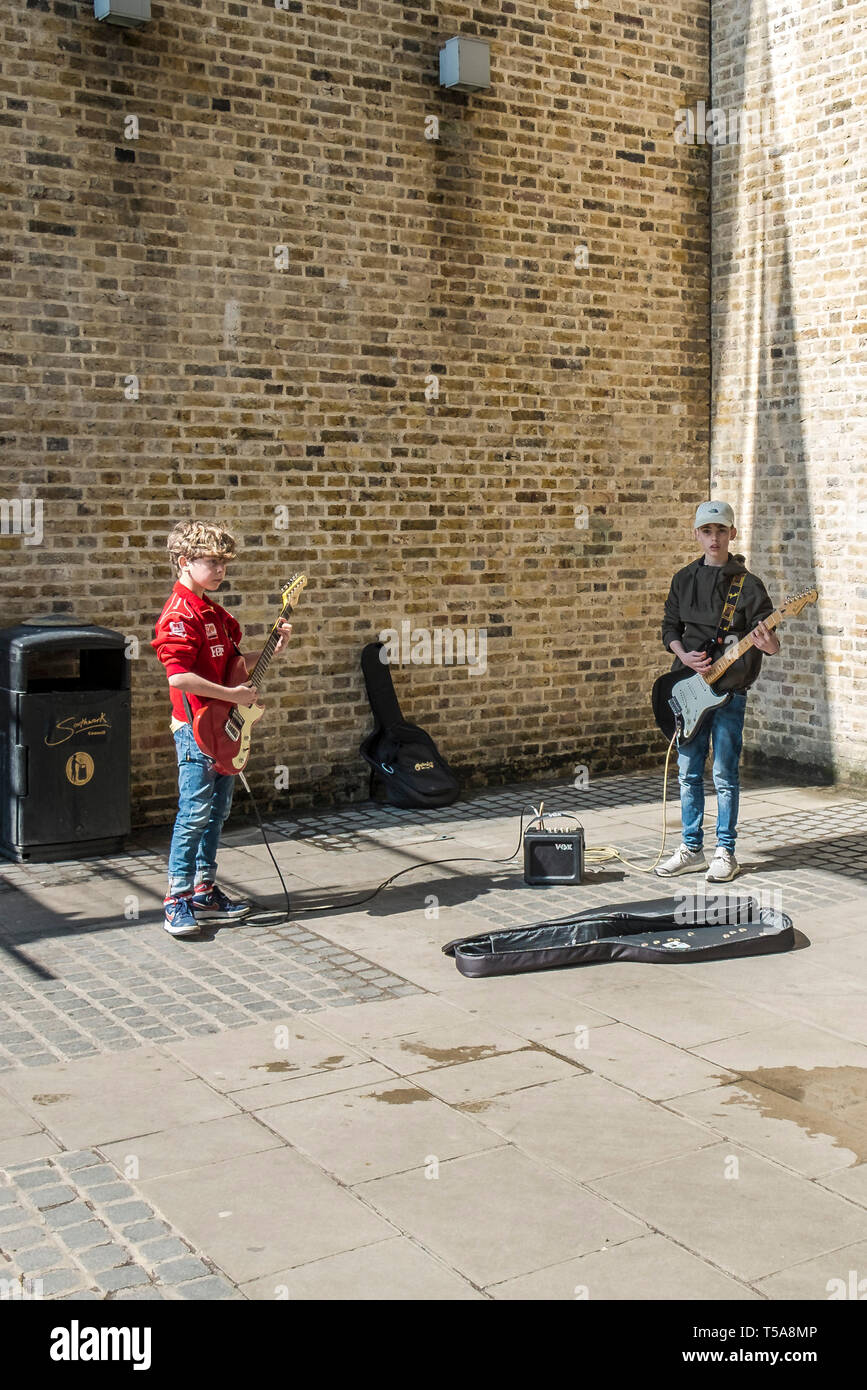 Two young boys playing electric guitars and busking in London Stock