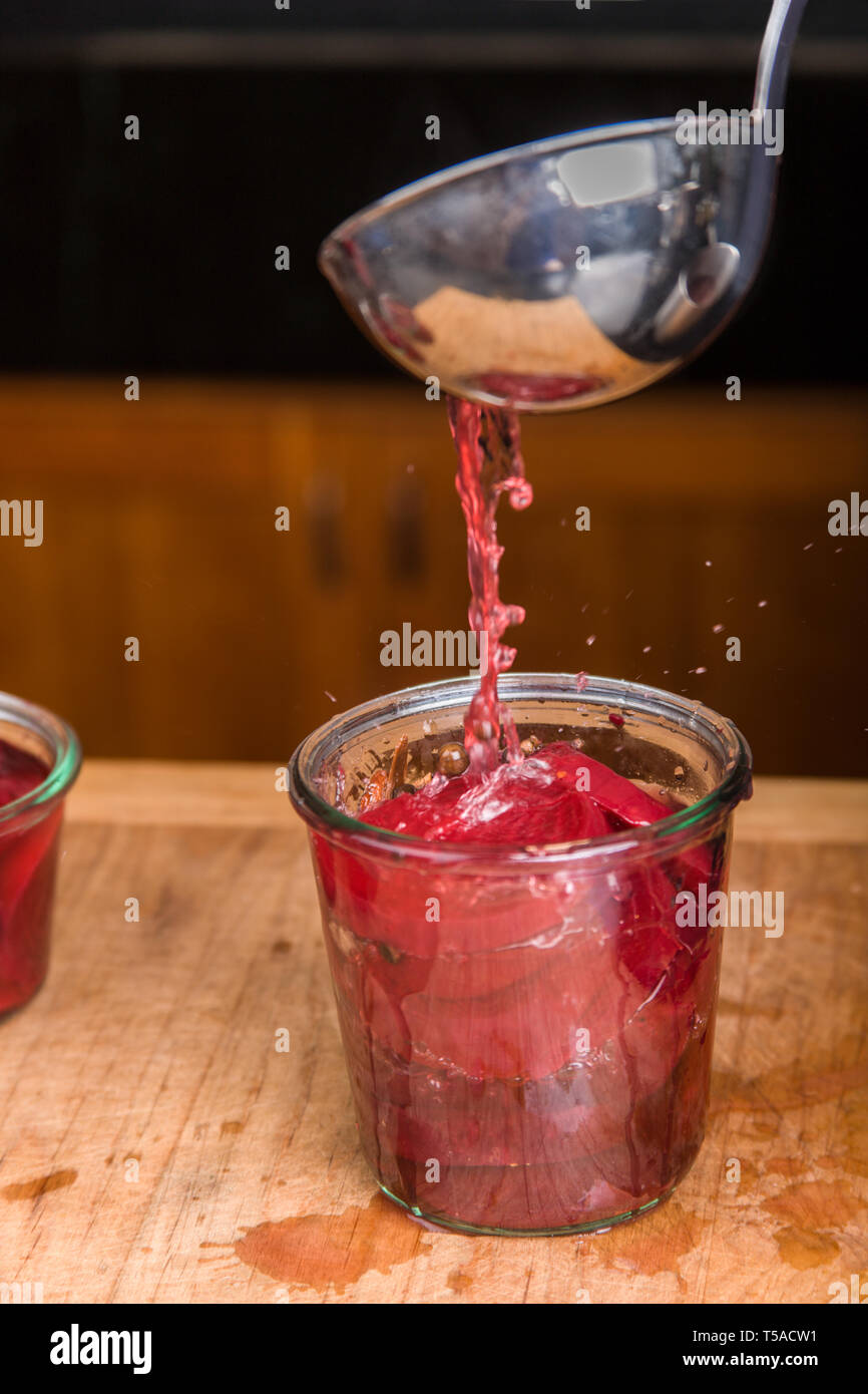 Pouring boiling pickling solution into a packed jar of beets. Stock Photo