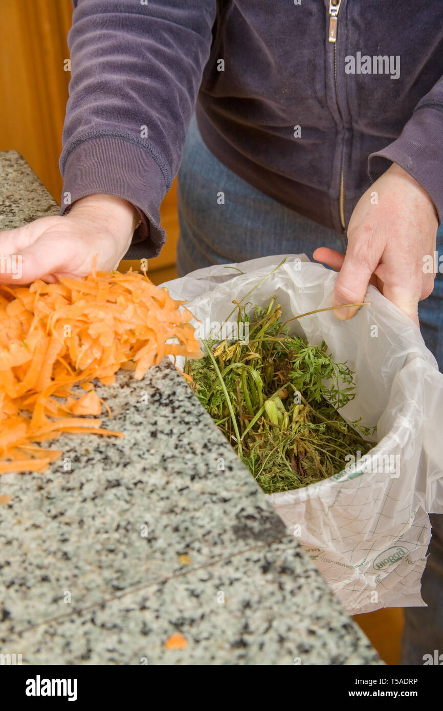 Pushing carrot peelings into a compost bucket in the kitchen. (MR Stock ...