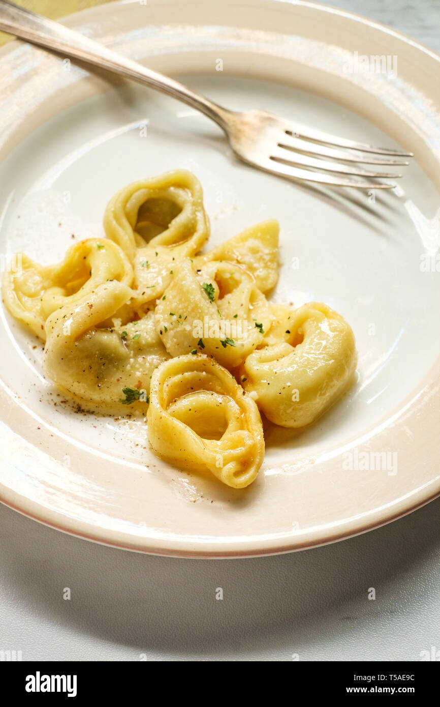 Tortellini with butter and parmesan cheese on marble kitchen table