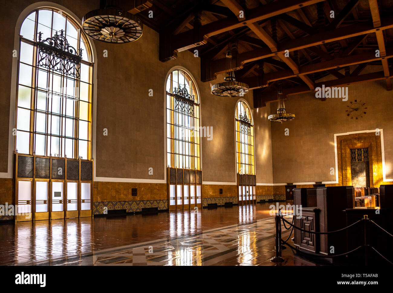 Inside historic Los Angeles Union Station with architectural details of tall Mission Revival windows and ceiling beams, with Art Deco light fixtures. Stock Photo