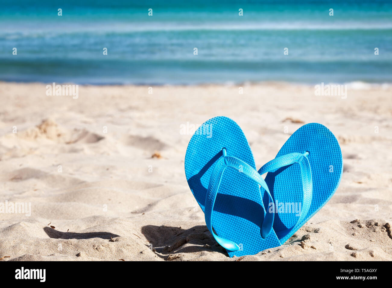 Blue flip flops on sand beach. Summer vacation concept Stock Photo - Alamy