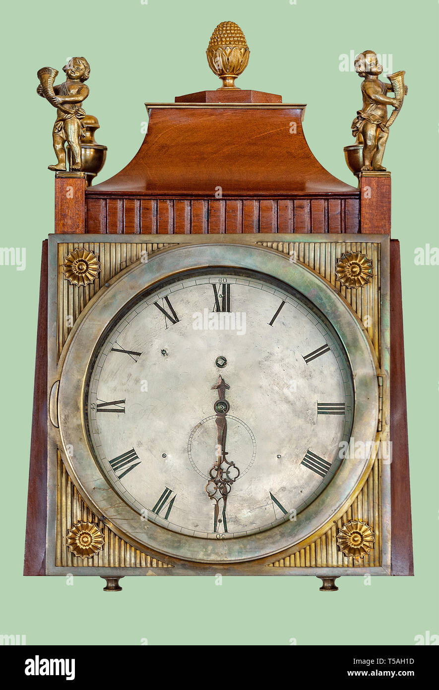 Antique mantel clock of brass children statuettes, on isolated green background with clipping path. Stock Photo