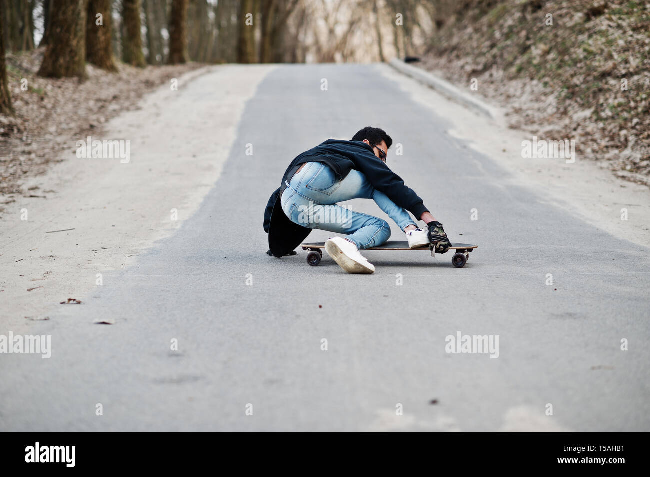 Fail falling from a skateboard. Street style arab man in eyeglasses with longboard  longboarding down the road Stock Photo - Alamy